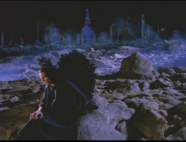 A screenshot from the 2004 documentary The Final Events of Bible Prophecy, depicting Satan sitting on a boulder on a desolate planet earth during the Millennium. Behind him the steeple of an empty dilapidated church rises into the gloom.